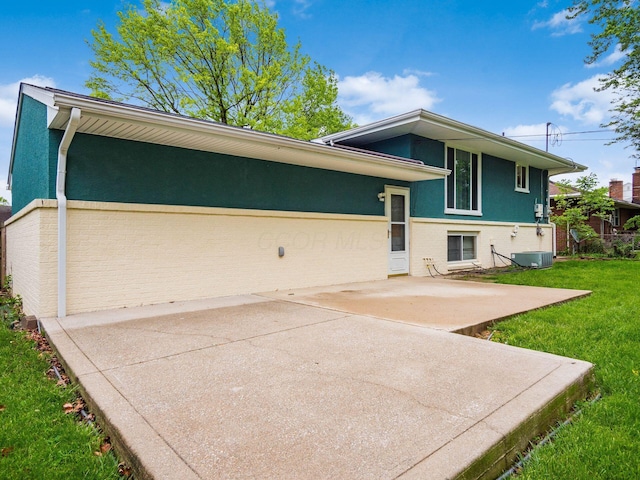 2852 Longfield Rd, Columbus, OH 43204 - view of front of house with central AC unit, a patio area, a front lawn, brick siding, and stucco siding