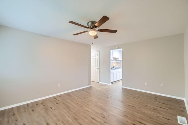 unfurnished room featuring ceiling fan, baseboards, light wood-style flooring, and a sink