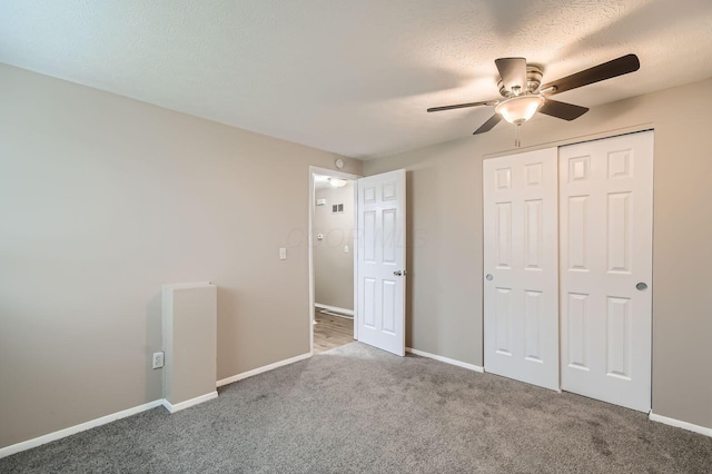 unfurnished bedroom with carpet flooring, a closet, baseboards, a textured ceiling, and ceiling fan