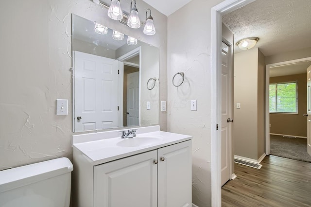 bathroom featuring vanity, wood finished floors, toilet, and baseboards