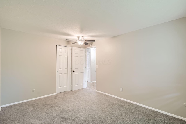 carpeted empty room with a ceiling fan and baseboards