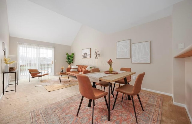 carpeted dining space with baseboards and vaulted ceiling