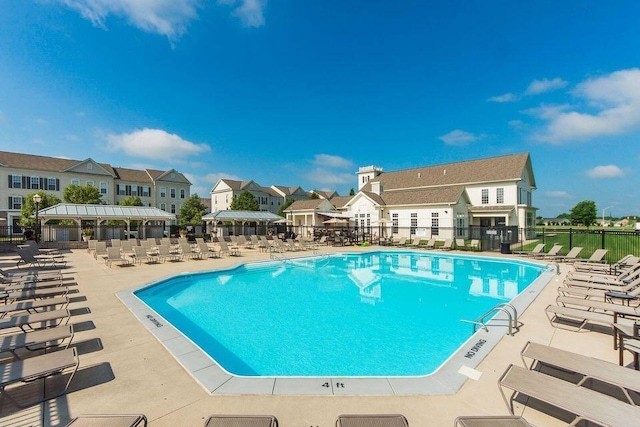 community pool featuring fence, a patio area, and a residential view