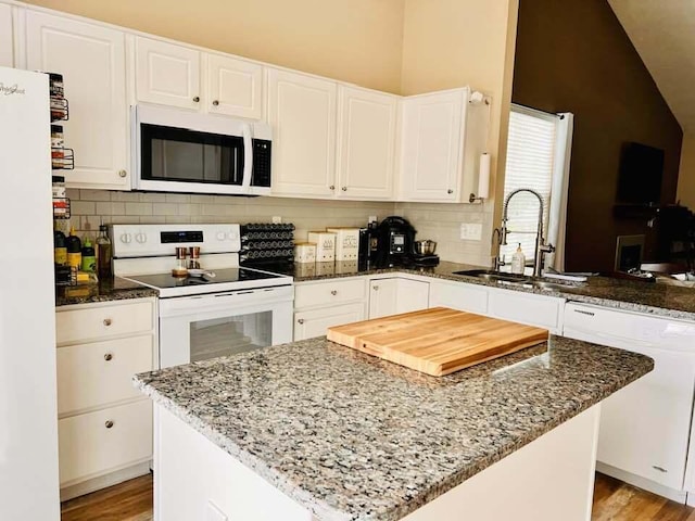 5492 Sentinel Falls St, Dublin, OH 43016 - kitchen with white appliances, a sink, vaulted ceiling, dark stone counters, and white cabinetry