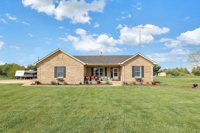 ranch-style house with covered porch, a chimney, brick siding, a front lawn, and a shingled roof