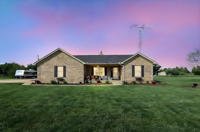 single story home with a yard, brick siding, and a porch