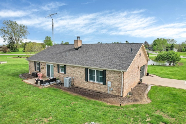 rear view of house featuring a lawn, brick siding, roof with shingles, and a chimney