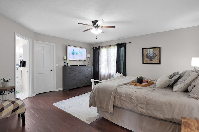 bedroom with a ceiling fan, baseboards, dark wood finished floors, and ensuite bath