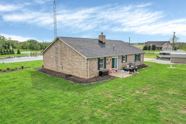 rear view of house featuring a chimney, brick siding, a yard, a patio, and a shingled roof