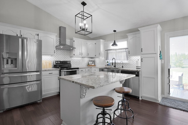 kitchen featuring white cabinets, appliances with stainless steel finishes, a sink, dark wood finished floors, and wall chimney exhaust hood