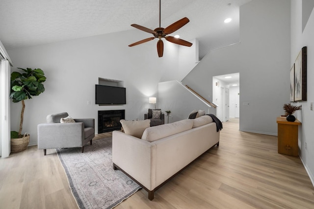 155 Arrowfeather Ln, Lewis Center, OH 43035 - living area featuring a ceiling fan, high vaulted ceiling, light wood finished floors, stairway, and a glass covered fireplace