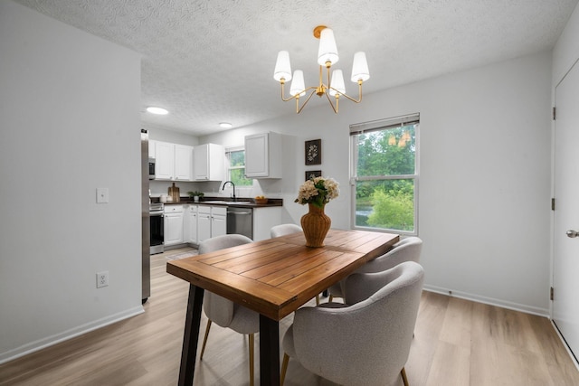 155 Arrowfeather Ln, Lewis Center, OH 43035 - dining area with light wood finished floors, a textured ceiling, plenty of natural light, a chandelier, and baseboards