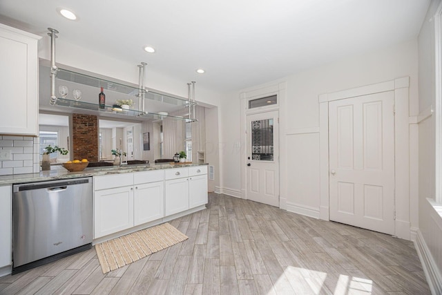 kitchen featuring stainless steel dishwasher, backsplash, white cabinetry, and light wood-style flooring
