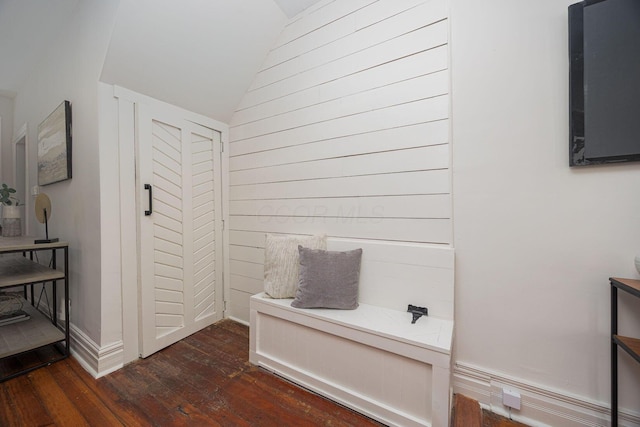 bathroom featuring lofted ceiling, hardwood / wood-style floors, and wooden walls