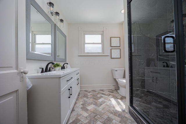 bathroom featuring a sink, double vanity, toilet, baseboards, and a shower stall