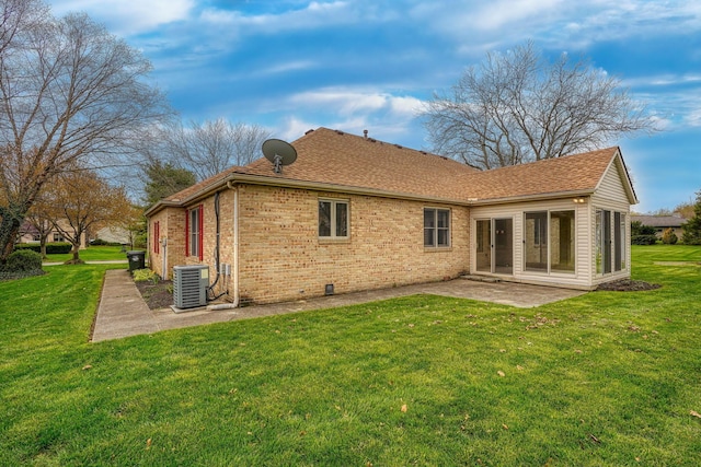 rear view of property with cooling unit, a sunroom, a lawn, a patio, and brick siding
