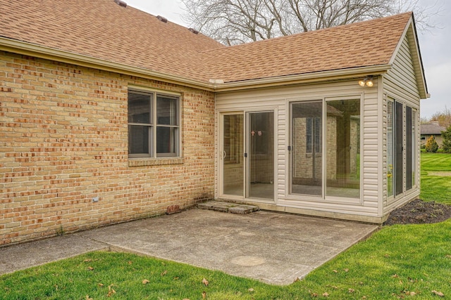 rear view of property with a shingled roof, a patio area, and brick siding