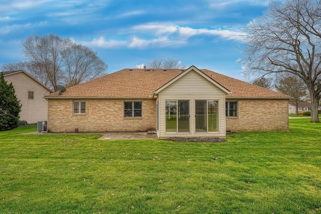 back of house featuring cooling unit, a lawn, roof with shingles, a patio area, and brick siding