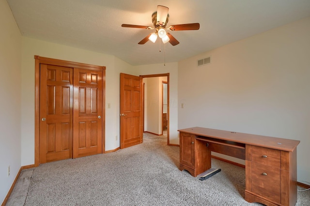 unfurnished office with carpet, visible vents, baseboards, and ceiling fan