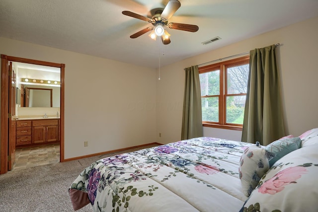 bedroom featuring ensuite bath, visible vents, light carpet, a sink, and baseboards