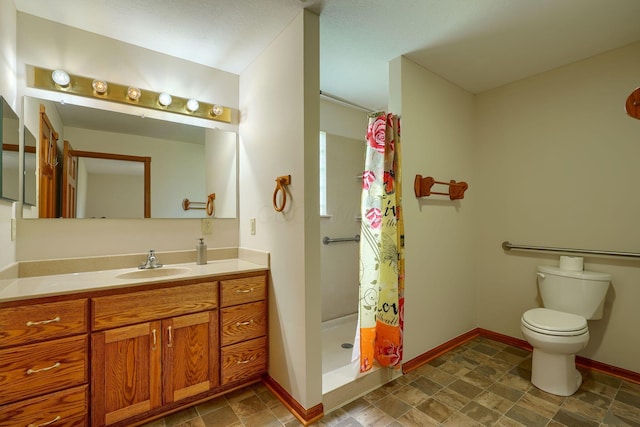 bathroom featuring vanity, a stall shower, baseboards, and toilet