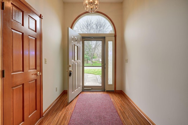 foyer featuring light wood-style flooring, a chandelier, and baseboards