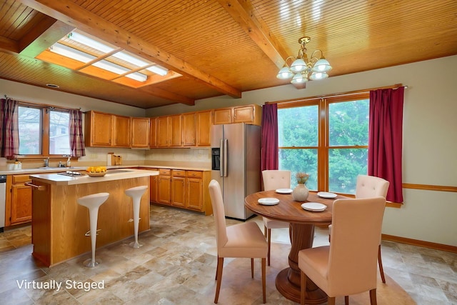 kitchen featuring a center island, light countertops, a chandelier, beam ceiling, and stainless steel appliances