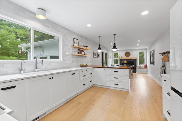 8019 Clouse Rd, New Albany, OH 43054 - kitchen with a peninsula, white cabinets, recessed lighting, light wood finished floors, and a fireplace