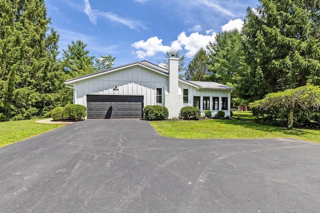 8019 Clouse Rd, New Albany, OH 43054 - view of front of home with board and batten siding, asphalt driveway, a chimney, a garage, and a front lawn
