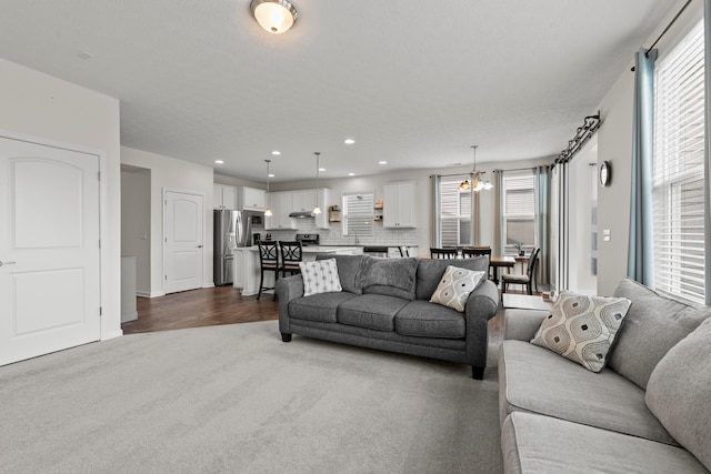 living room with a healthy amount of sunlight, recessed lighting, an inviting chandelier, and dark colored carpet