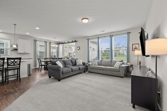 living room featuring a textured ceiling, recessed lighting, wood finished floors, and a chandelier