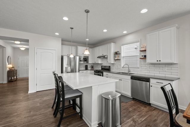 kitchen with a kitchen breakfast bar, white cabinetry, a sink, backsplash, and stainless steel appliances