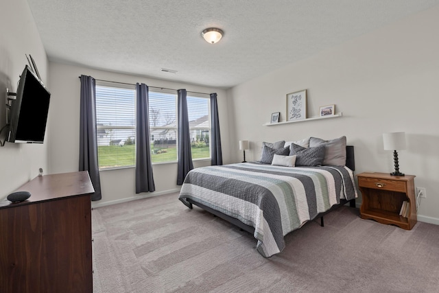 bedroom with a textured ceiling, light carpet, and baseboards