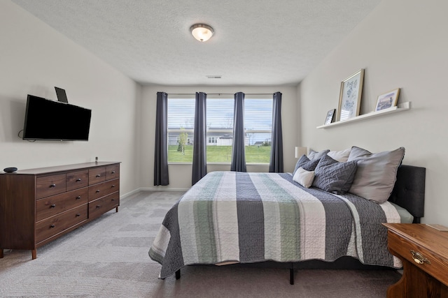 bedroom featuring baseboards, light carpet, and a textured ceiling