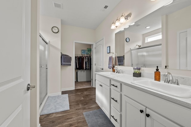 bathroom with a sink, a spacious closet, a stall shower, and visible vents