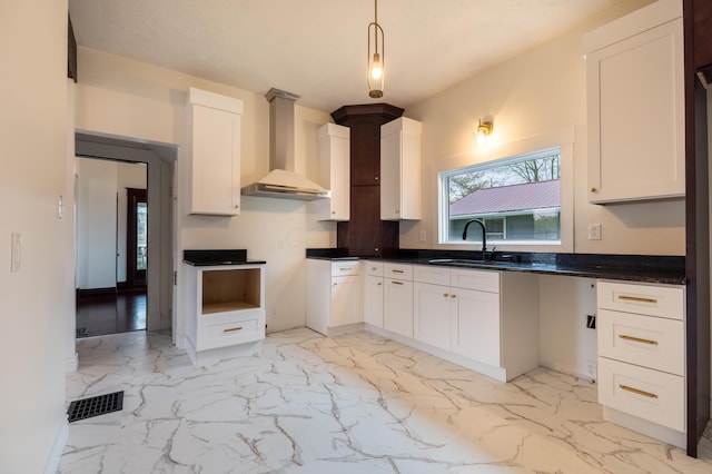 kitchen with marble finish floor, visible vents, wall chimney exhaust hood, and a sink