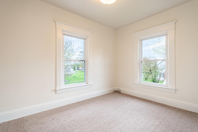 empty room with a wealth of natural light, carpet, and baseboards