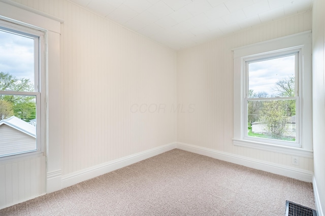 carpeted empty room with plenty of natural light and visible vents