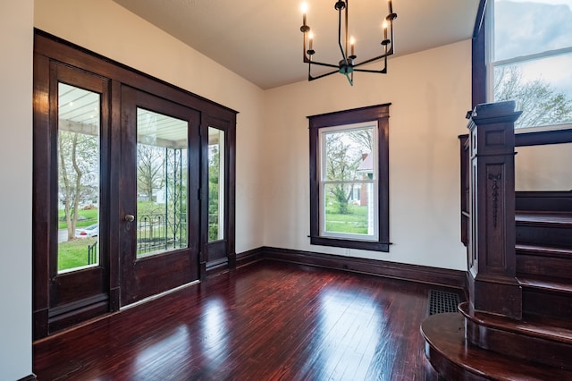 entrance foyer with visible vents, stairway, a chandelier, hardwood / wood-style floors, and baseboards
