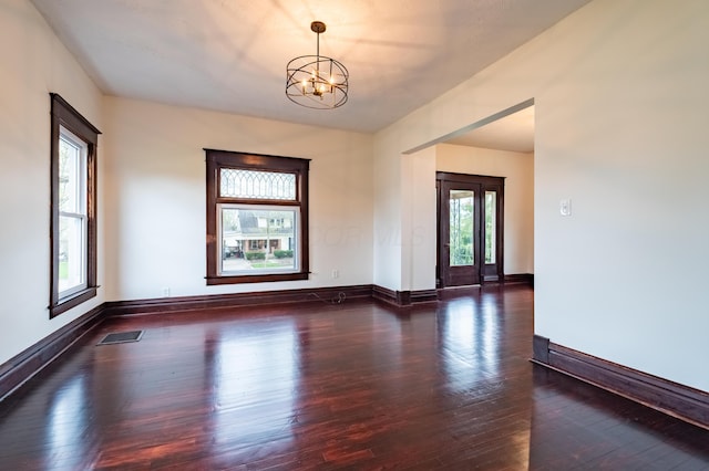 spare room with hardwood / wood-style floors, a notable chandelier, and visible vents