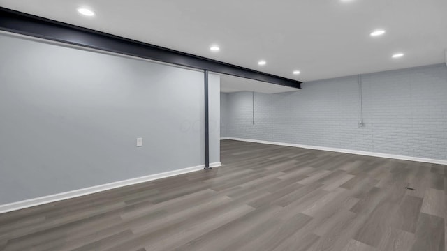 finished basement with brick wall, wood finished floors, baseboards, and recessed lighting