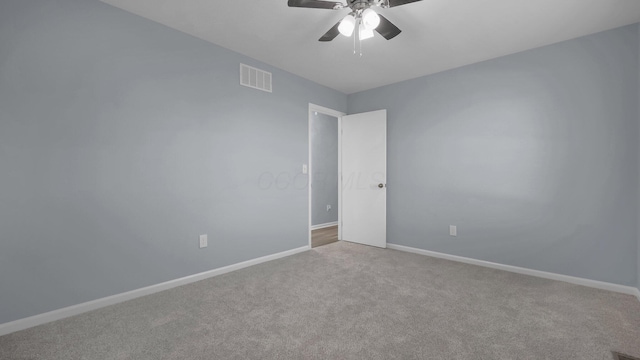 carpeted spare room featuring baseboards, a ceiling fan, and visible vents