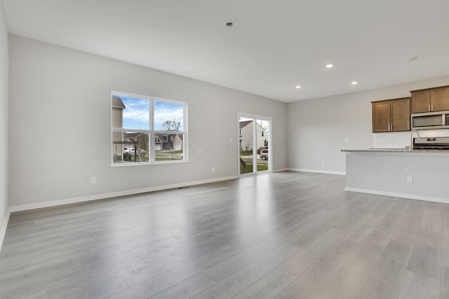 unfurnished living room with light wood-style flooring, recessed lighting, and baseboards