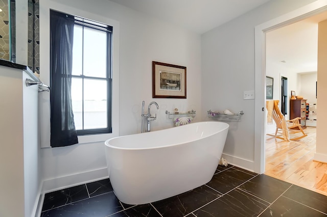 9730 Lancaster Kirkersville Rd NW, Baltimore, OH 43105 - bathroom featuring a freestanding bath, baseboards, a healthy amount of sunlight, and marble finish floor