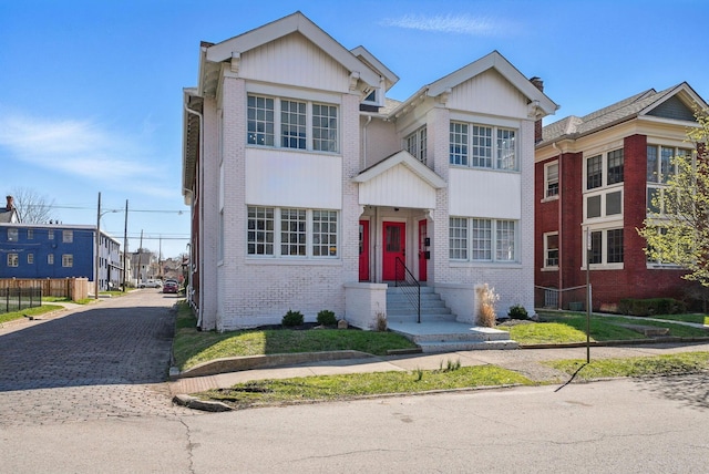 view of front facade with brick siding, fence, and driveway