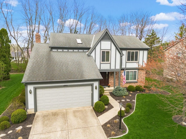 tudor house with concrete driveway, roof with shingles, a chimney, and a front yard