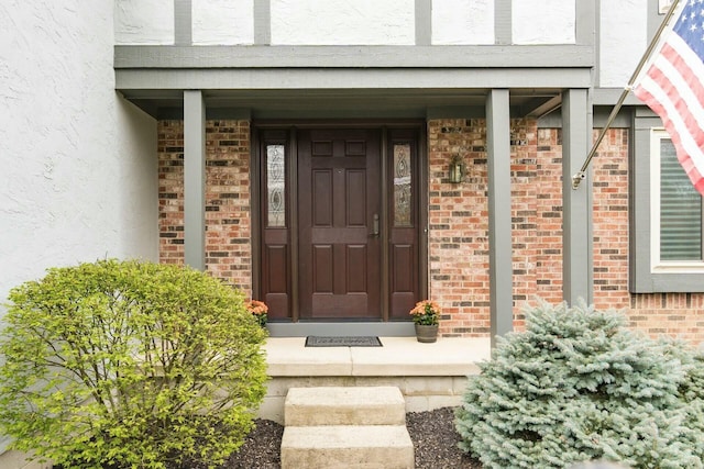 property entrance with stucco siding and brick siding