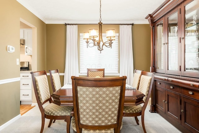 dining space with ornamental molding, light carpet, a notable chandelier, and baseboards