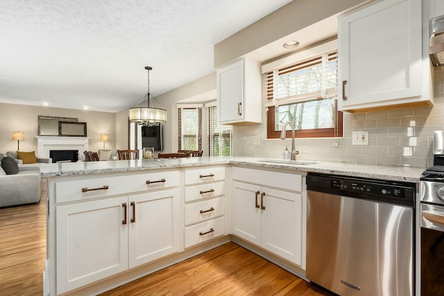 kitchen featuring stainless steel appliances, a peninsula, a sink, and a healthy amount of sunlight