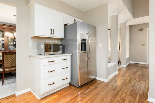 kitchen featuring light wood-type flooring, stainless steel appliances, white cabinets, and light stone countertops